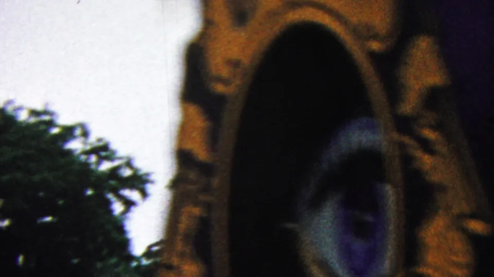 A warm-toned arched decorative element or float detail fills the frame as a blurred person moves nearby in the 1961 parade footage.