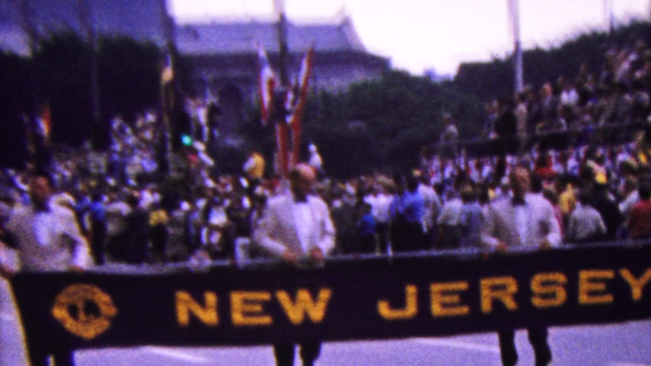 Parade marchers carry the NEW JERSEY banner with spectators behind them.