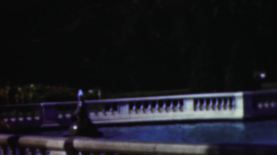 1953 Cleveland 8mm frame with a white balustrade, blue fountain pool, dark foreground statue or fountain form, and shaded trees in the background.