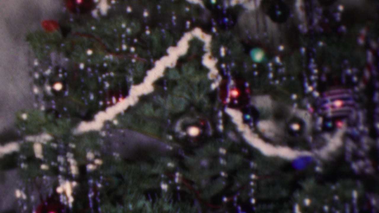Close 1953 Cleveland home-movie view of a Christmas tree with dark branches, white garland, silver tinsel, small lights, and glass ornaments.