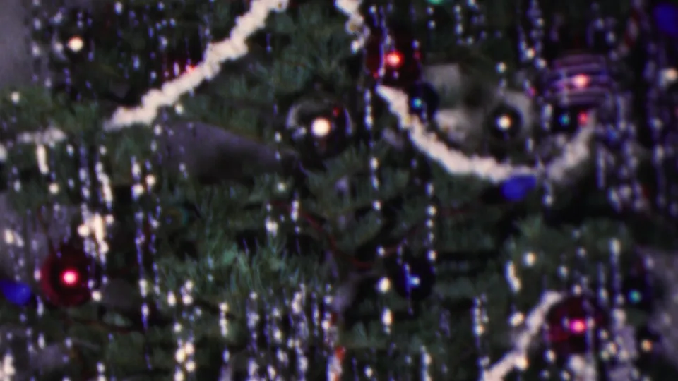 1953 Cleveland 8mm close-up of a decorated Christmas tree with silver tinsel, white garland, colored glass ornaments, and small lights in soft focus.