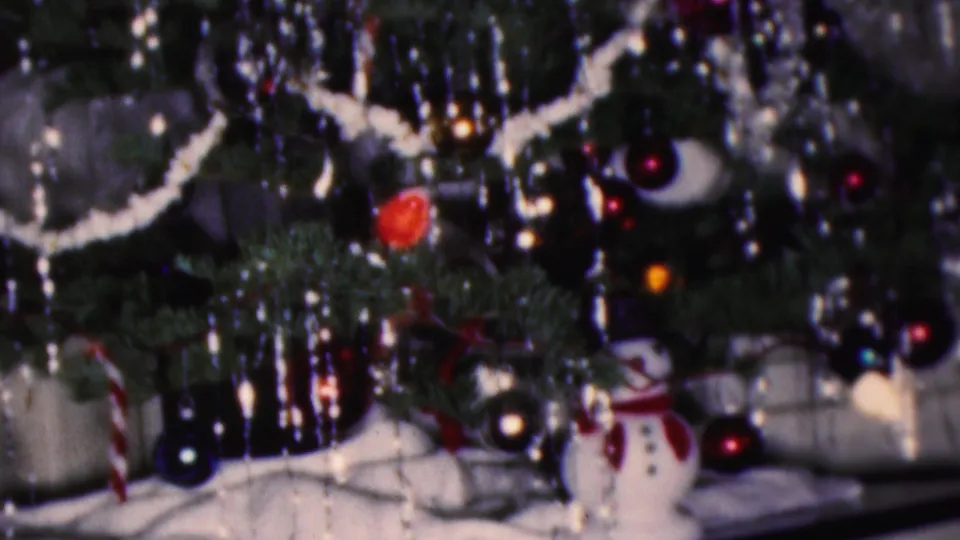 1953 Cleveland 8mm frame showing a close, soft-focus view of Christmas tree decorations, white garland, ornaments, and small snowman figures.