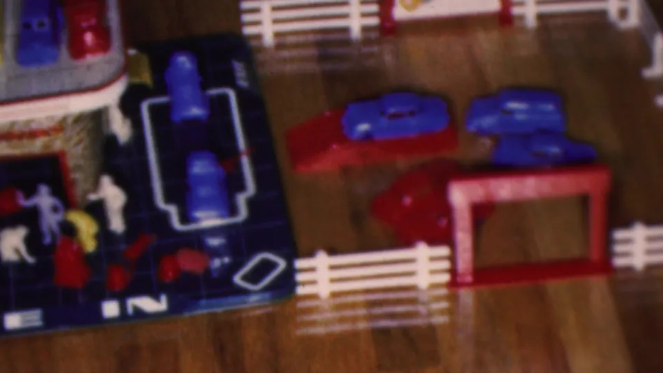 Cleveland, Ohio 1953 frame showing a colorful toy drive-in garage playset with small cars, figures, fences, and plastic accessories on the floor.