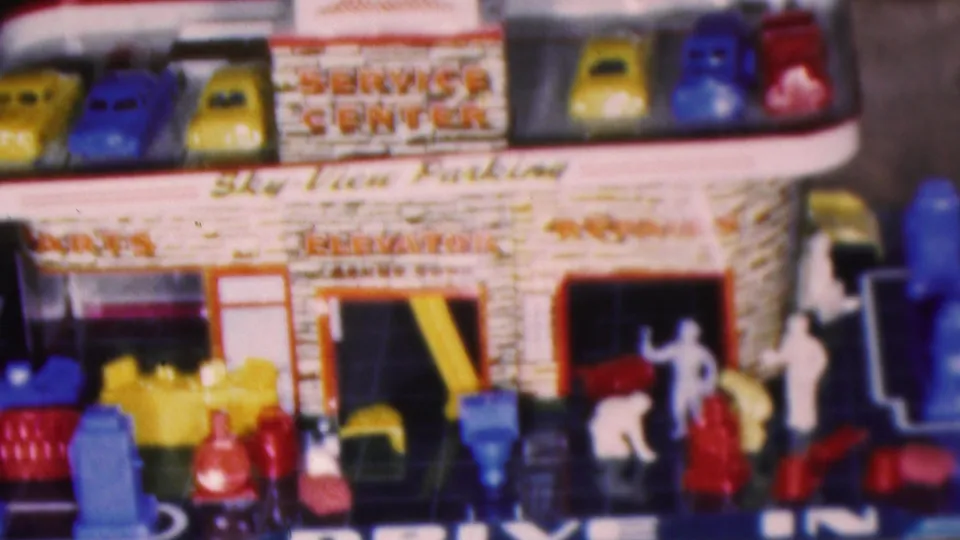 Close 8mm frame of the toy service center facade, showing Sky View Parking lettering, Service Center signage, colorful roof cars, garage bays, and small figures near the entrance.