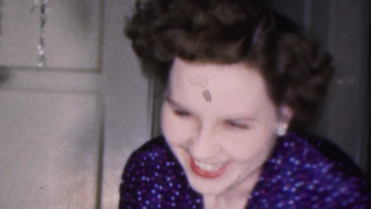 Woman leaning forward and smiling beside a white paneled door.
