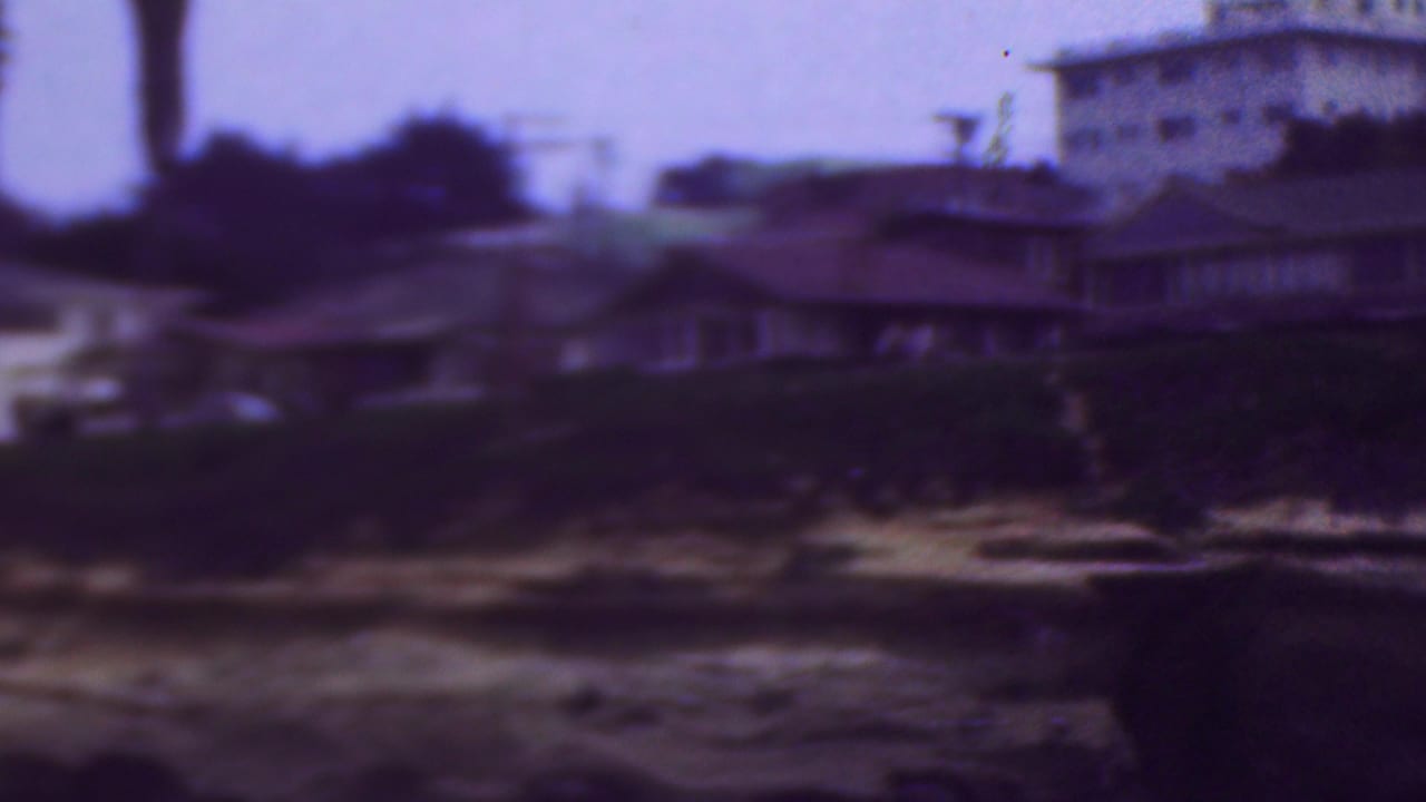 Soft-focus waterfront houses above dark water and sandy shoreline.