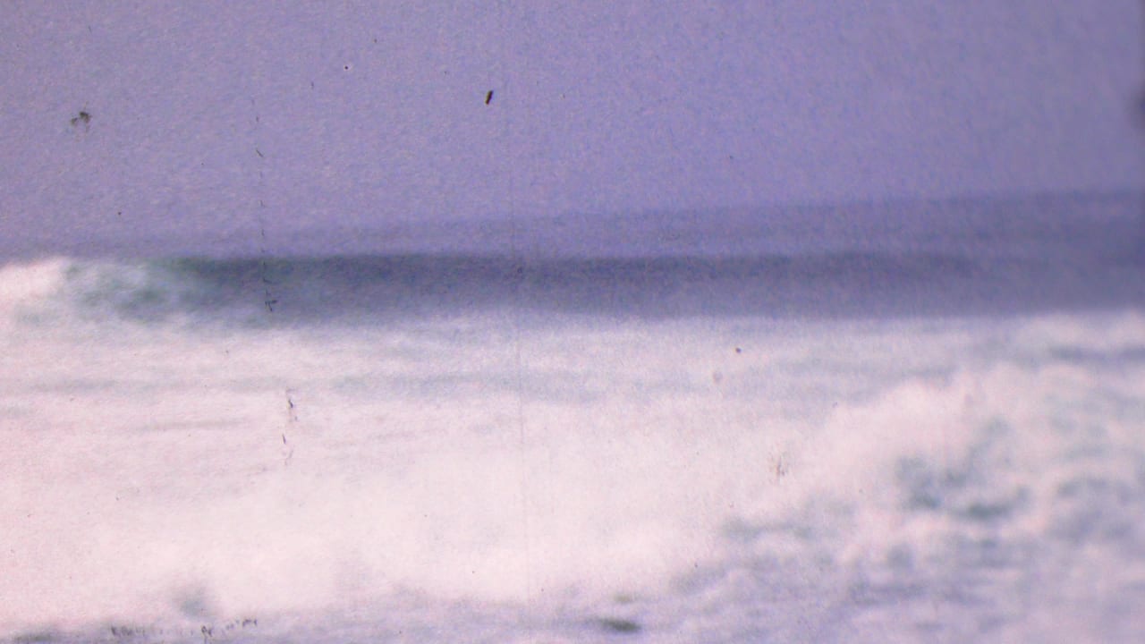 1953 8mm frame associated with Cleveland, Ohio, showing whitecaps and blurred surf beneath a dim overcast sky.