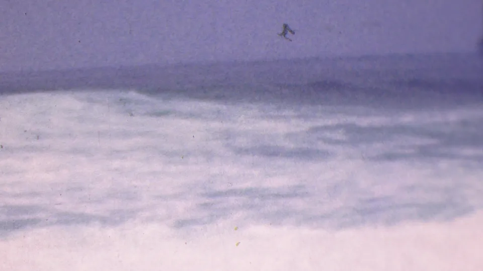 1953 8mm frame associated with Cleveland, Ohio, showing foamy water and a dark distant surf band under an overcast sky.