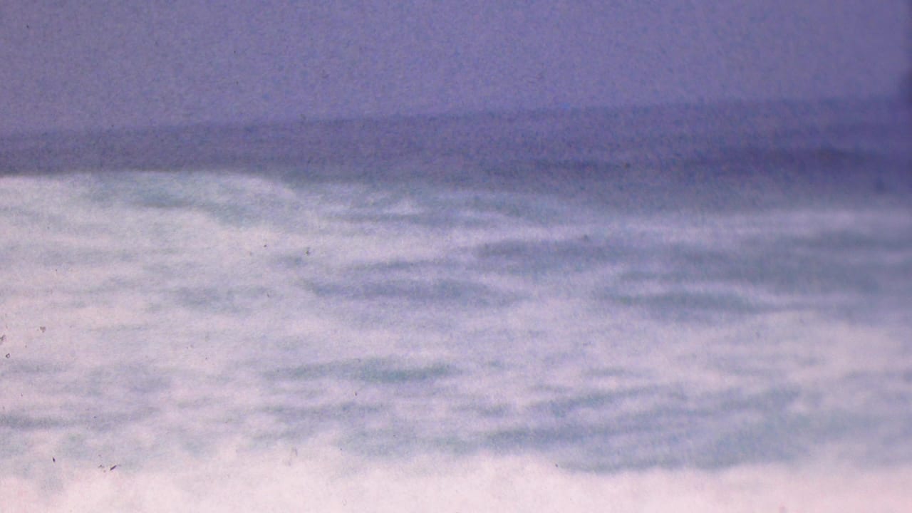 1953 Cleveland, Ohio metadata frame showing rough open water beneath a soft, cloudy horizon with faded blue-purple 8mm color.
