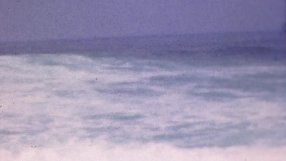 1953 Cleveland, Ohio metadata frame showing rough open water beneath a soft, cloudy horizon with faded blue-purple 8mm color.