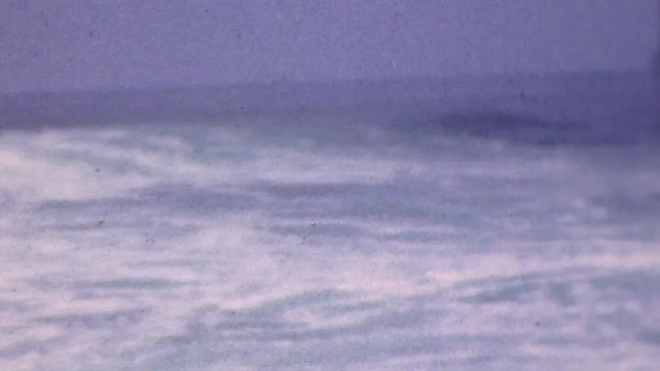 Faded 8mm frame of rolling, wind-tossed water with a pale horizon line and cloudy sky, associated by metadata with Cleveland, Ohio in 1953.