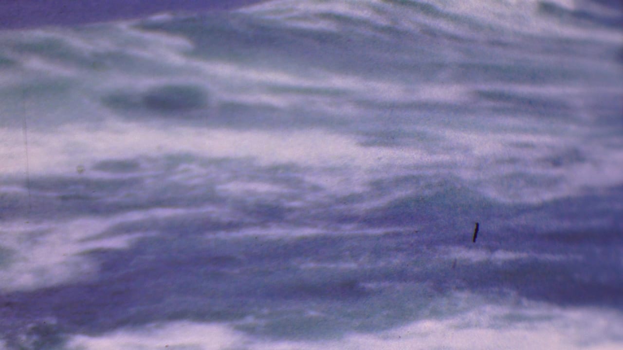 Soft, grainy 1953 8mm footage shows churning ocean waves with no people visible in this frame.