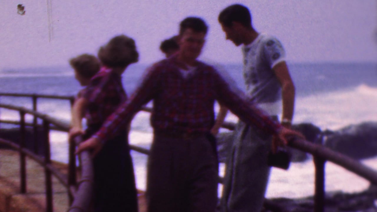 Young adults in mid-century casual clothing stand and talk beside a curved waterfront pier railing in footage identified as Cleveland, Ohio, 1953.