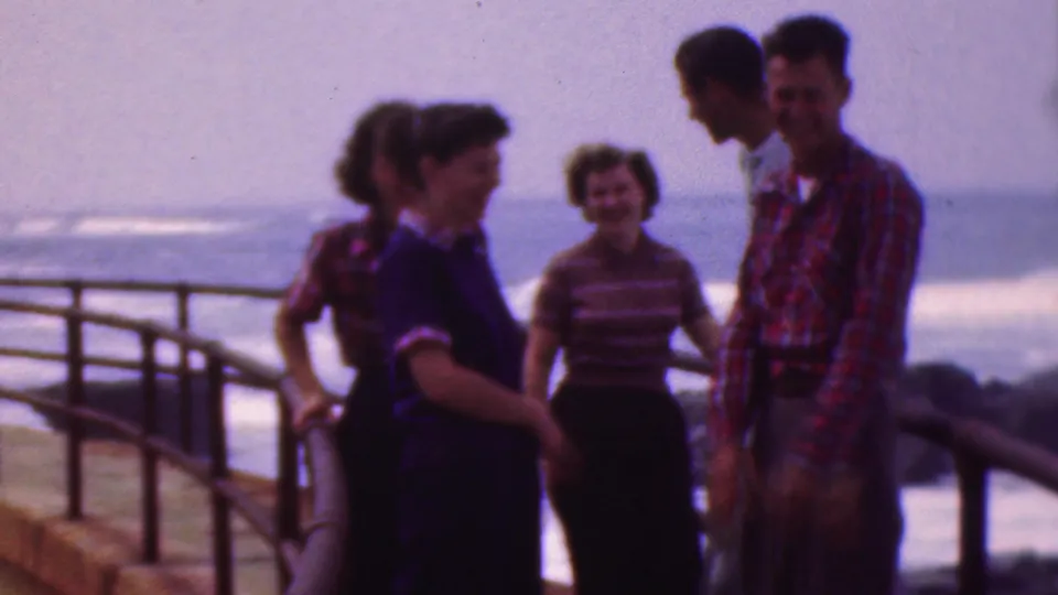 Four young adults stand together on the waterfront pier in the Cleveland, Ohio, 1953 footage, with a curved railing and surf visible behind the group.