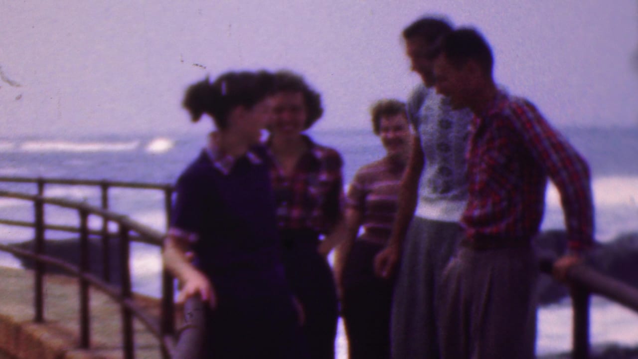 Five young adults in 1950s-style casual clothing socialize by a curved metal railing near open water, consistent with the supplied Cleveland, Ohio 1953 metadata.