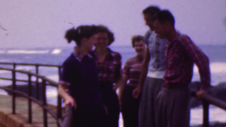 Five young adults in 1950s-style casual clothing socialize by a curved metal railing near open water, consistent with the supplied Cleveland, Ohio 1953 metadata.