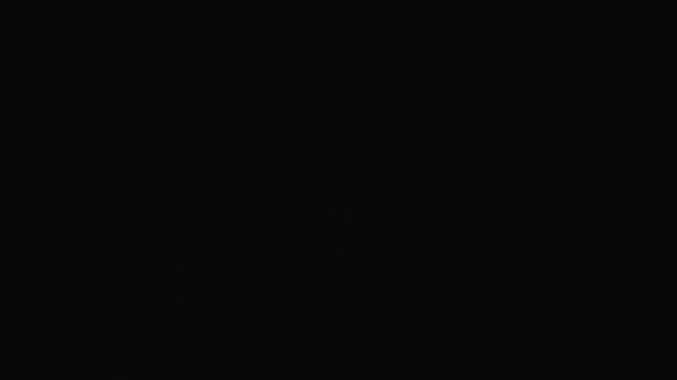Underexposed 8mm frame from the 1953 Cleveland clip, with the previous waterfront scene largely obscured by dark exposure and faint color grain.