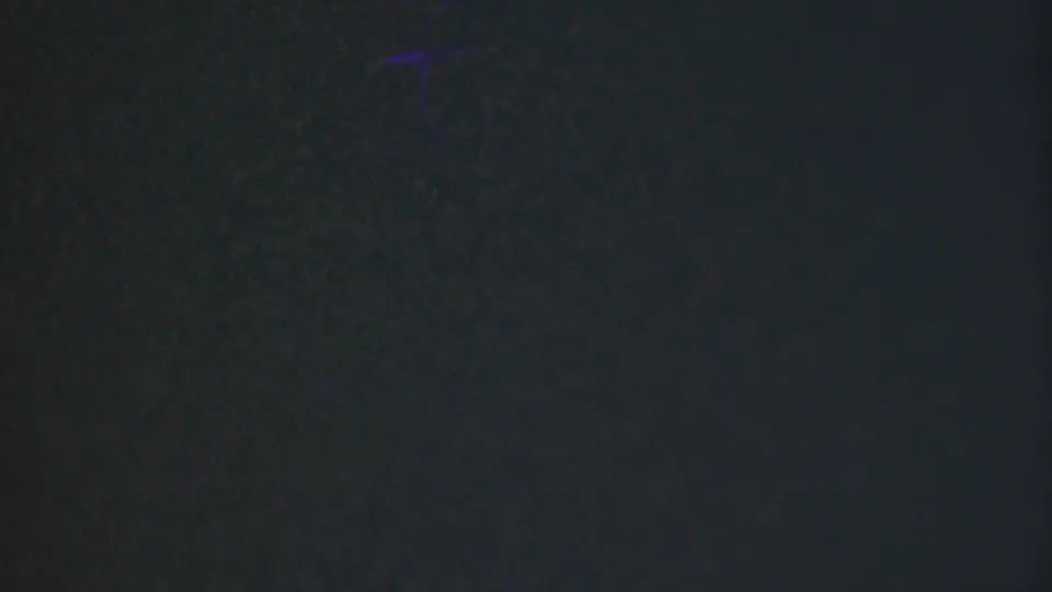 Soft, dark 8mm frame from the Cleveland home movie with faint bluish-green grain and no clearly distinguishable people or objects in this still.