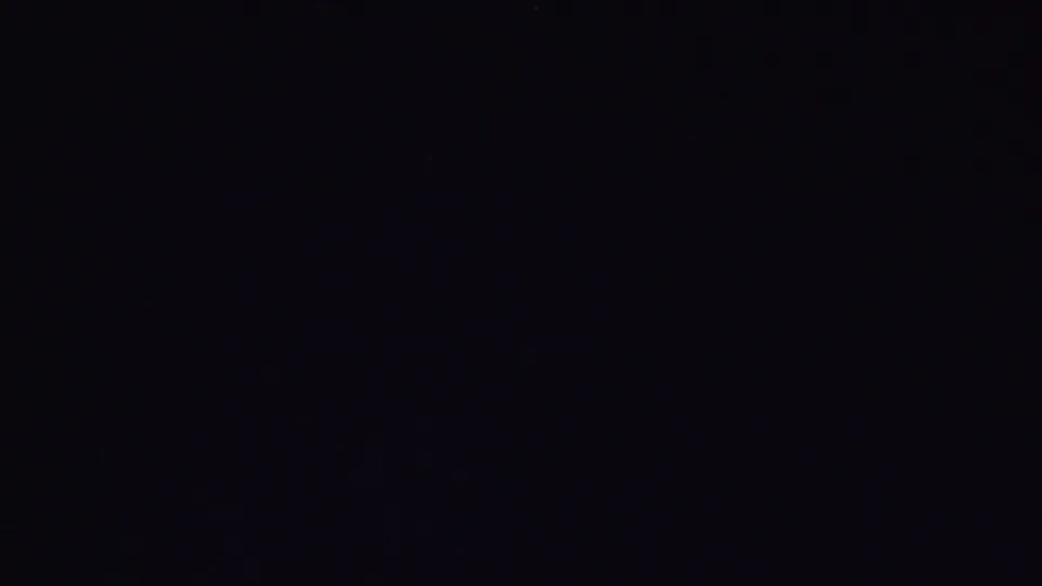 Very dark 8mm frame with only faint traces of the previous interior visible, likely near the end of the brief home-movie shot.