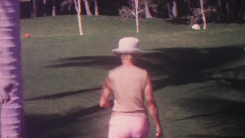 At the end of the 1962 Hawaii home-movie clip, the woman walks toward a red croquet ball on a broad green lawn framed by palm trunks and deep shadows.