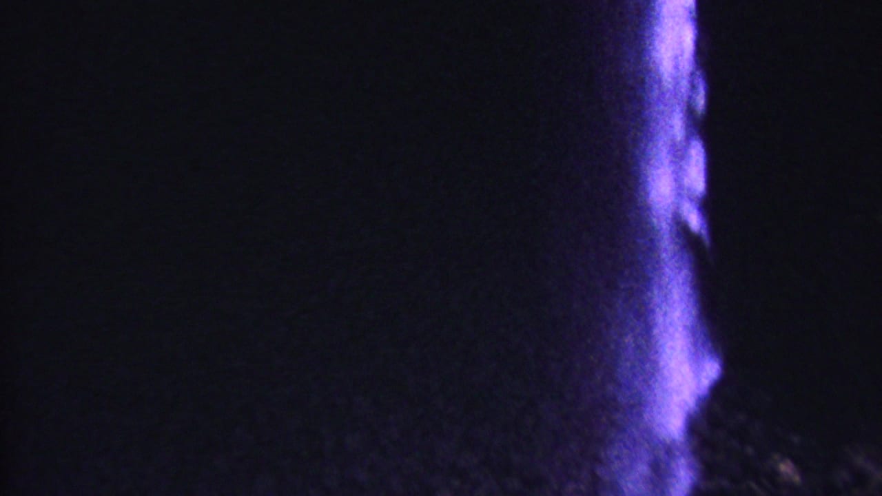 Dark cliff face with a purple-lit vertical stream at the right.