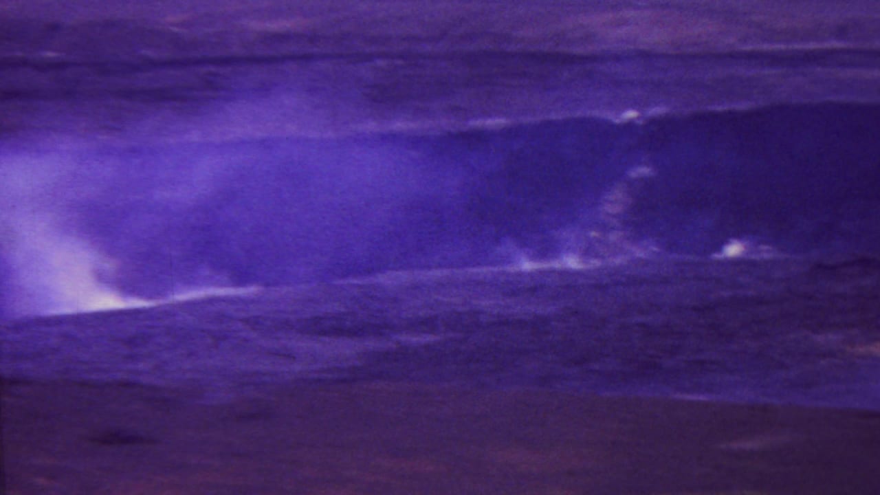1962 Hawaii 8mm frame with a low volcanic fissure or vent releasing steam across dark open terrain, heavily tinted by aged film color.