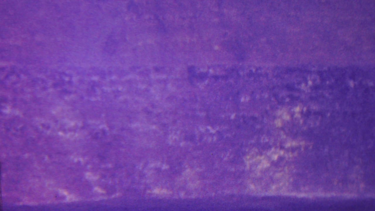 Soft, purple landscape view with textured cliff or hillside across the frame.