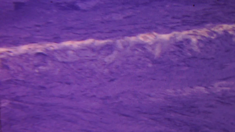 1962 Hawaii 8mm frame showing a closer section of purple-shifted rock or ground, including a brighter ridge-like band and darker textured areas.