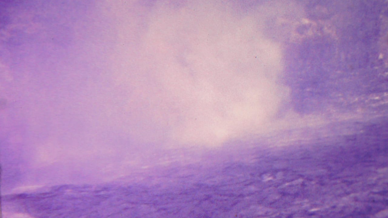 White steam rises over dark volcanic terrain under a purple sky.