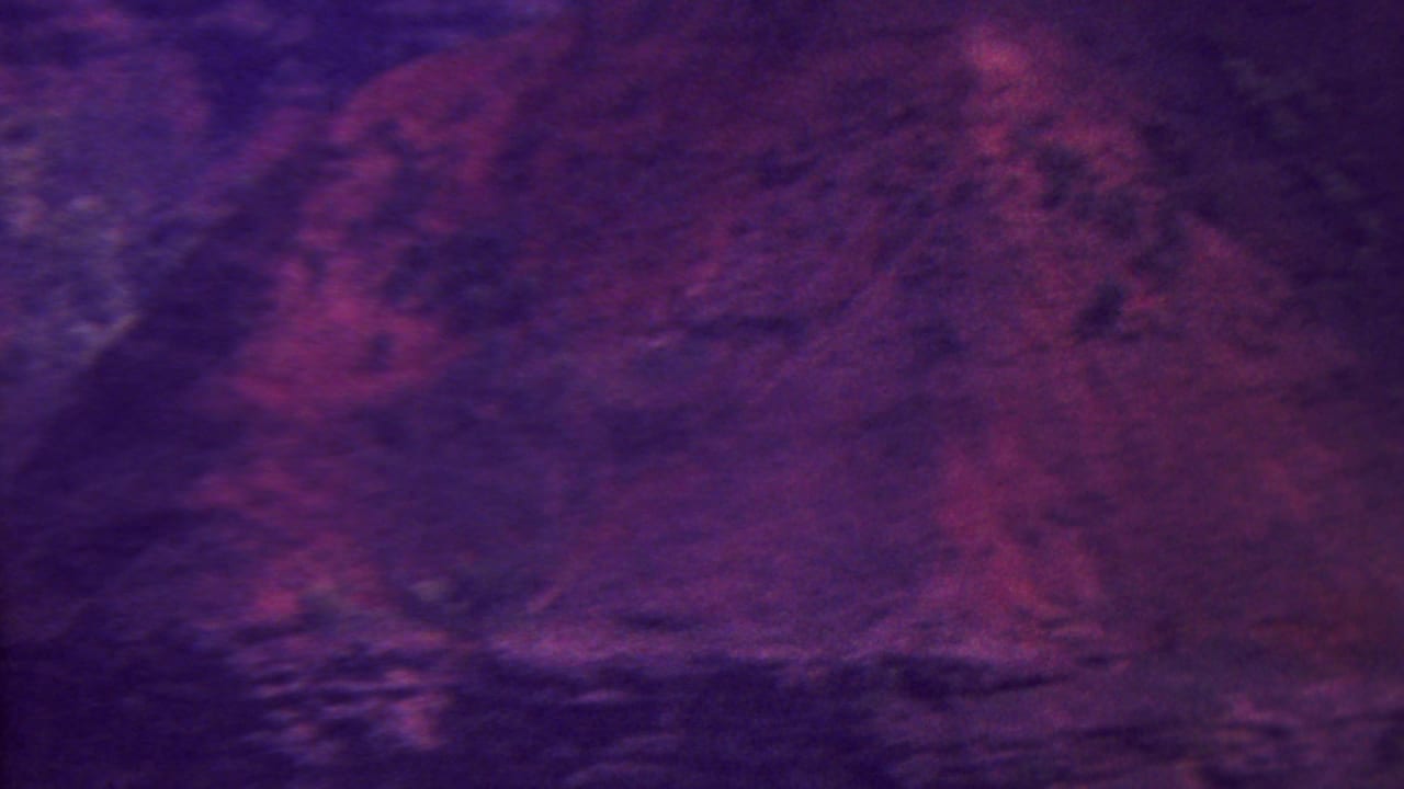 1962 Hawaii 8mm home-movie frame showing steep, shadowed mountain terrain with purple and magenta film color shift.