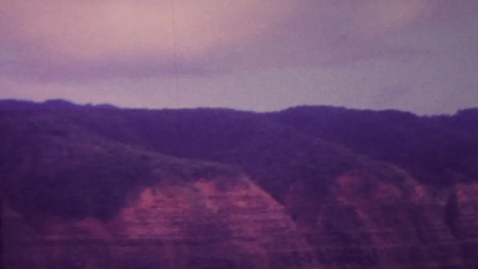 The final sampled frame shows a reddish, layered cliff face and a dark ridge line under a purple dusk sky, consistent with the source-described 1962 Hawaii home movie.