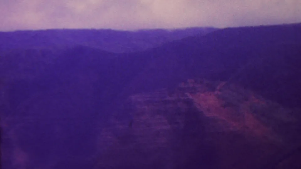 1962 Hawaii 8mm frame with a broad, shadowed mountain panorama, layered canyon forms, and muted sky color from aged film stock.