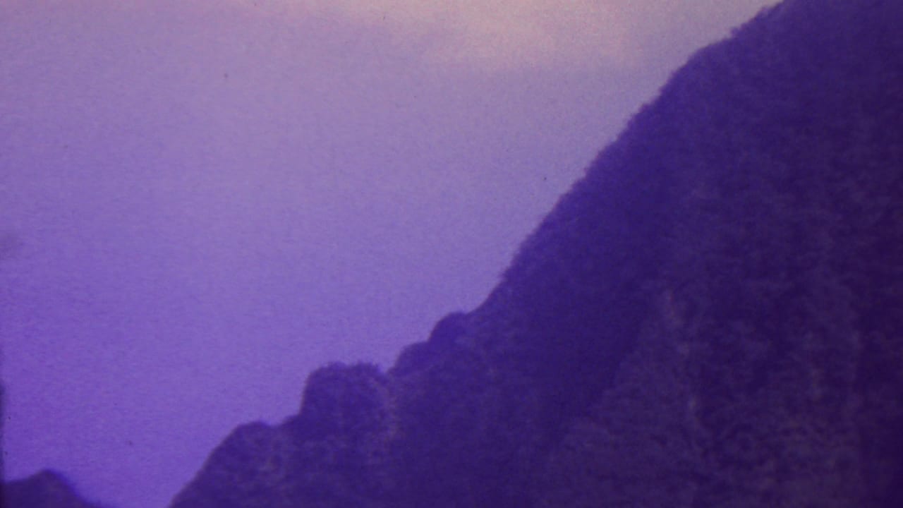 Steep mountain slope and lower rocky forms under a purple sky.