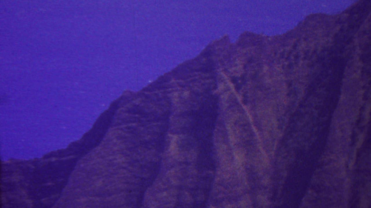 1962 Hawaii 8mm frame with a steep shadowed mountain face and a small bright point in the upper sky, possibly a distant light source.
