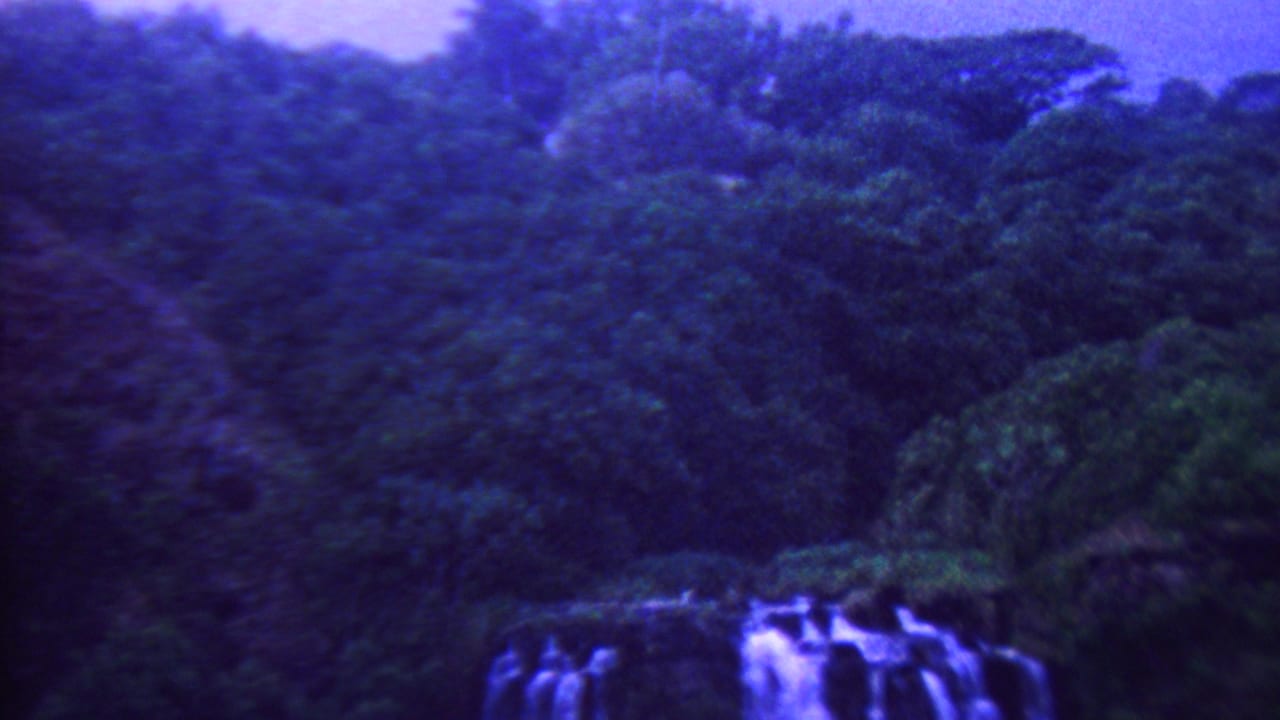 A waterfall appears below thick tropical forest in purple-blue tinted 1962 Hawaii 8mm travel footage.