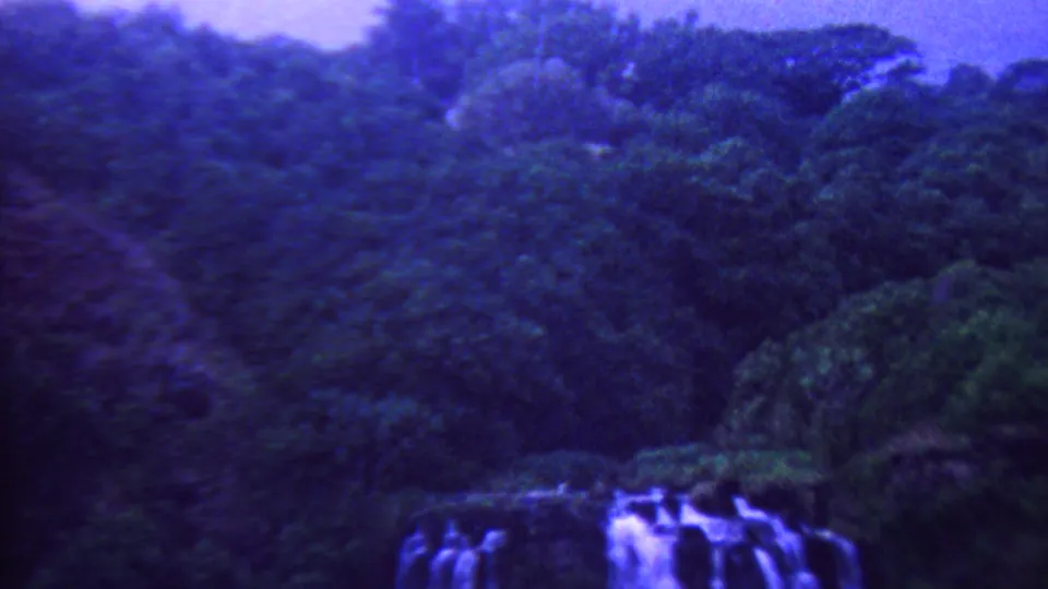 A waterfall appears below thick tropical forest in purple-blue tinted 1962 Hawaii 8mm travel footage.