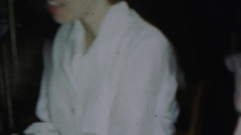 A woman in a light robe or shirt is partly captured in the lower-left frame of this 1954 Columbus, Ohio 8mm indoor home-movie scene.