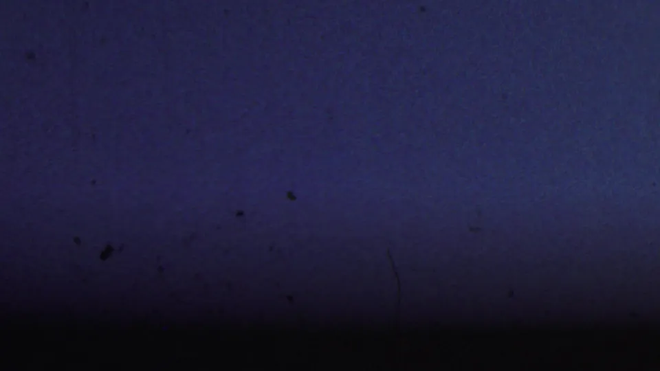 The final 8mm frame shows mostly dark blue exposed film texture with dust, scratches, and a darker band across the lower portion.