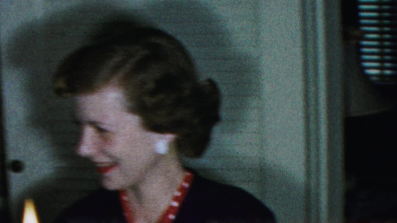Smiling woman turns toward another person beside a lit candle.