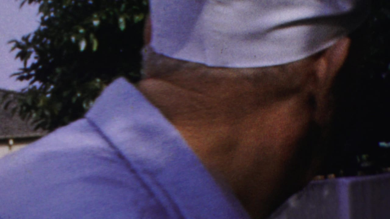 Two older men in white caps outdoors, one seen from behind and one facing the camera.