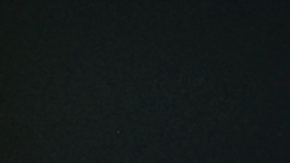 Near the end of the clip, the restaurant interior is very underexposed, leaving only faint shapes of the table area and seated people visible in grainy greenish 8mm texture.