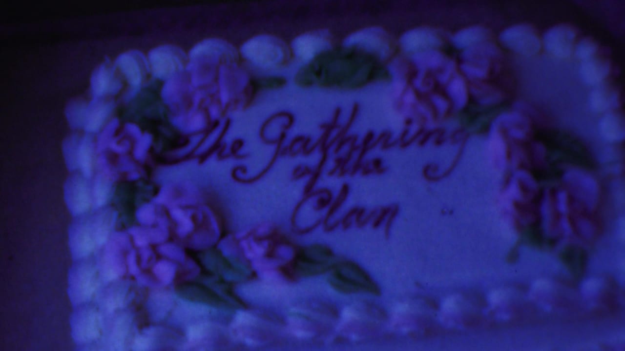 Decorated frosted cake with purple flowers and The Gathering of the Clan written in icing.