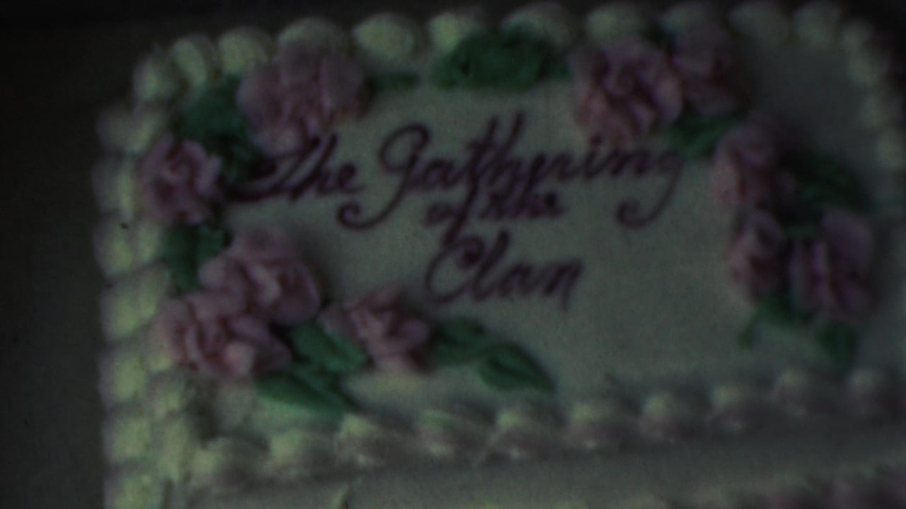 Close-up from 1949 8mm home-movie footage in Seaside, New Jersey, showing a decorated cake inscribed The Gathering of the Clan with pink frosting flowers and green leaves.