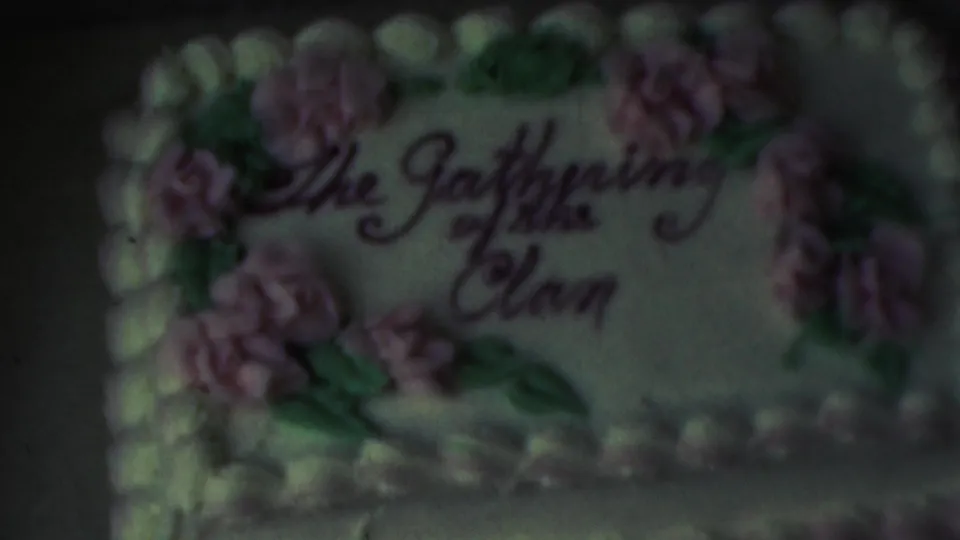 Close-up from 1949 8mm home-movie footage in Seaside, New Jersey, showing a decorated cake inscribed The Gathering of the Clan with pink frosting flowers and green leaves.