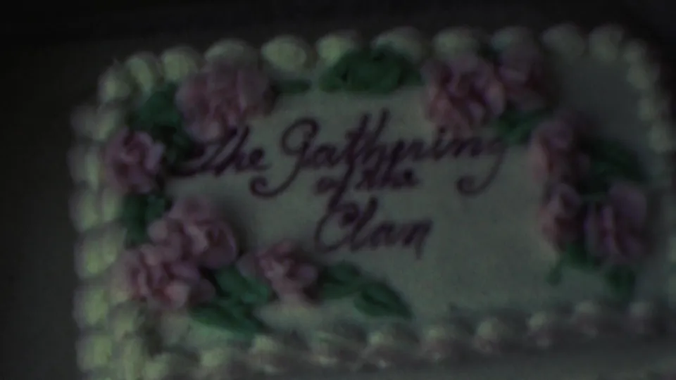 The 8mm frame holds on the decorated gathering cake, with the cursive inscription, pastel flowers, green leaves, and white frosting border visible in soft mid-century color.
