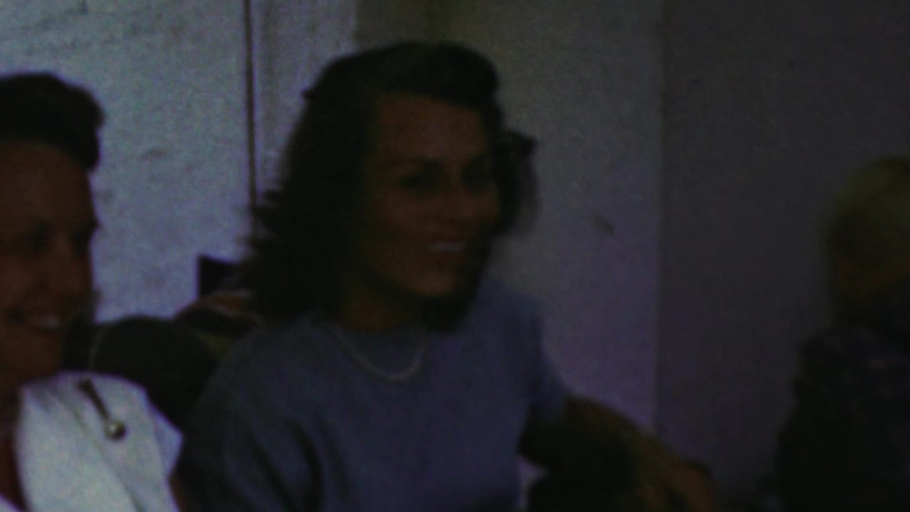 Guests smiling in a dimly exposed outdoor gathering scene.
