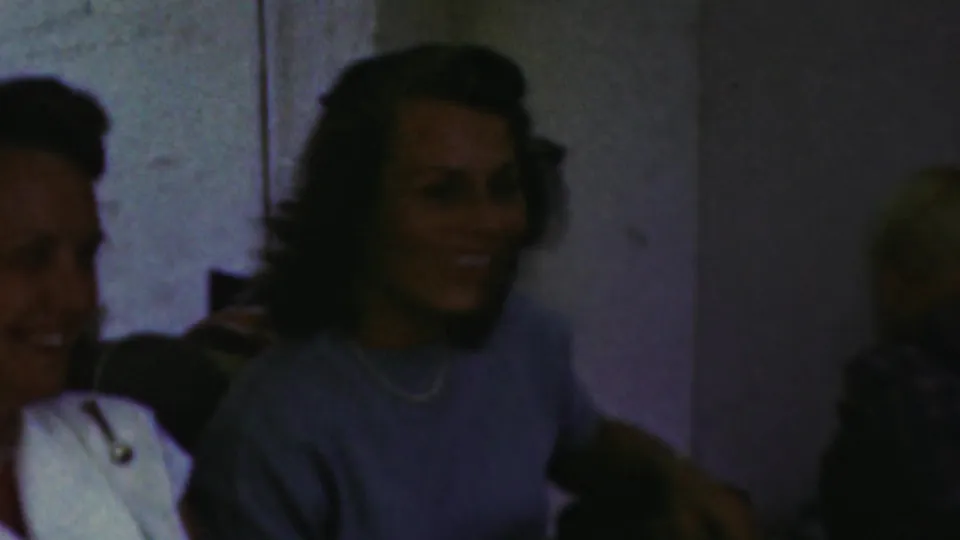 At a 1949 Seaside, New Jersey family gathering, smiling guests are partially visible in soft, dark 8mm footage.