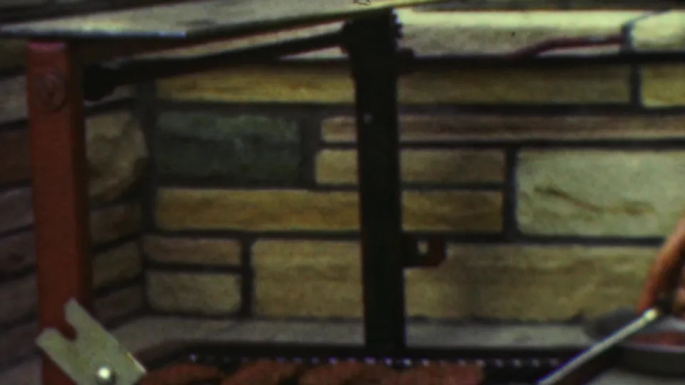 The final frame centers on the brick grill and black metal rail, with part of the cook's arm and a utensil visible at the lower right edge.