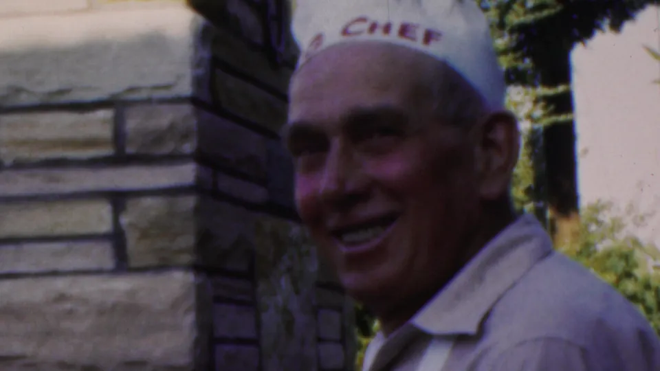 The same Seaside, New Jersey 1949 home-movie shot shows a man in a white chef hat smiling beside stonework with greenery behind him.