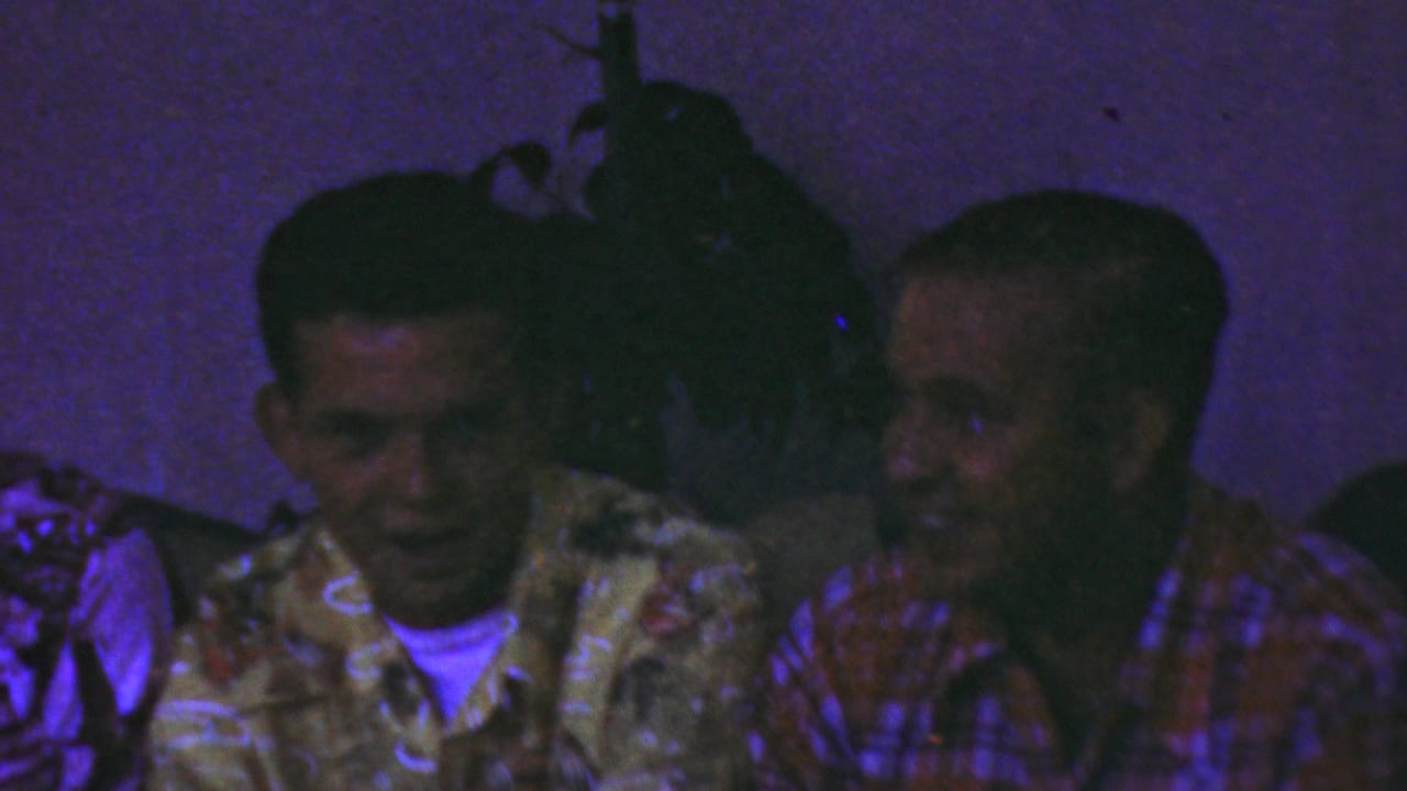 Adult men in patterned shirts sit close together in a dim private interior, consistent with the supplied 1949 Seaside, New Jersey home-movie metadata.